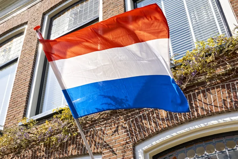 dutch flag waving in the wind on the facade of a typical dutch house on koningsdag a national holiday in the kingdom of the netherlands