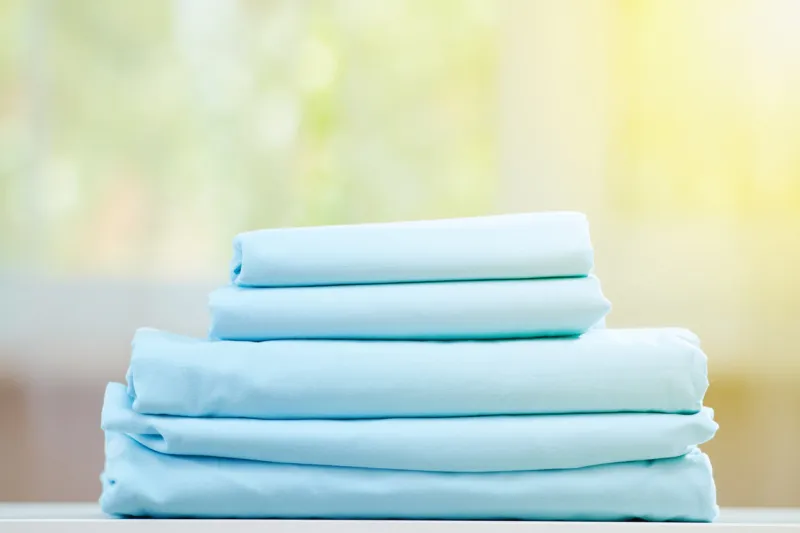 blue colored bedding on a blurred background stack of folded new sheets on the table