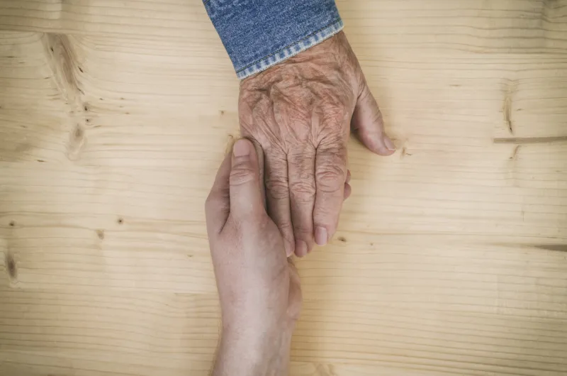 male hand holds the hand of an elderly woman lots of texture and character in the old ladies hand