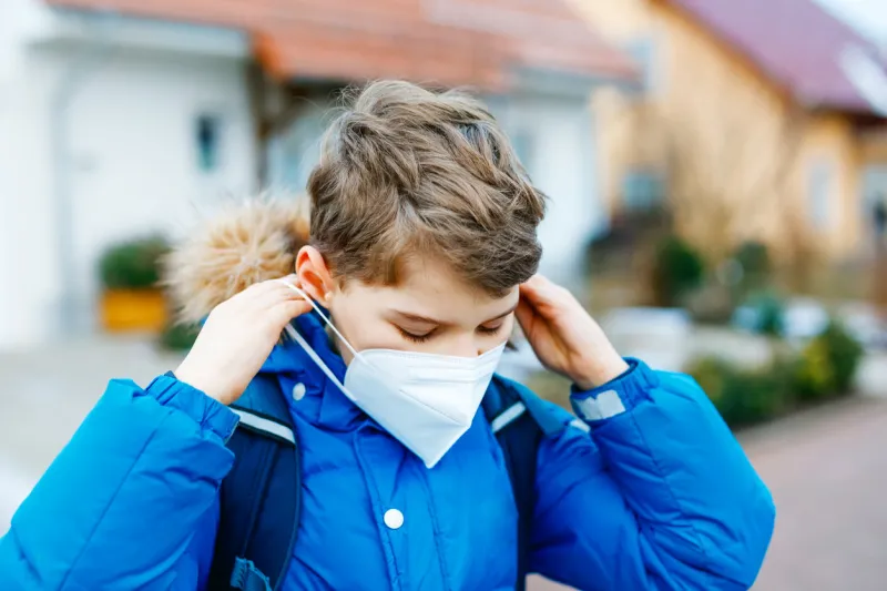 kid boy wearing ffp medical mask on the way to school child backpack satchel schoolkid on cold autumn or winter day with warm clothes lockdown and quarantine time during corona pandemic disease