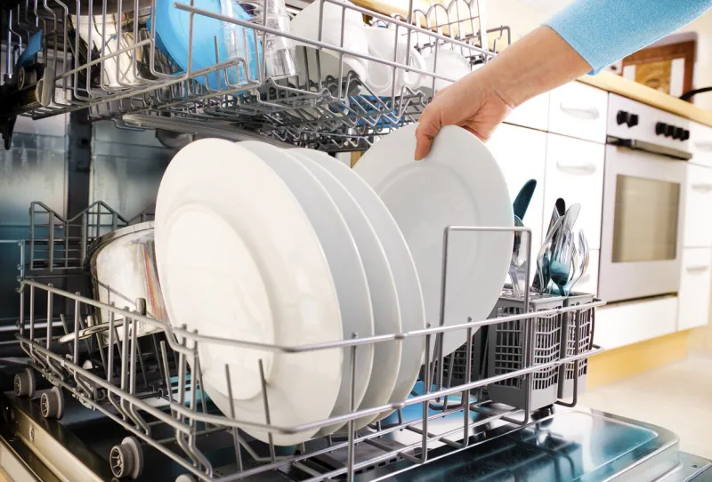 close-up of female hands loading dishes to the dishwasher