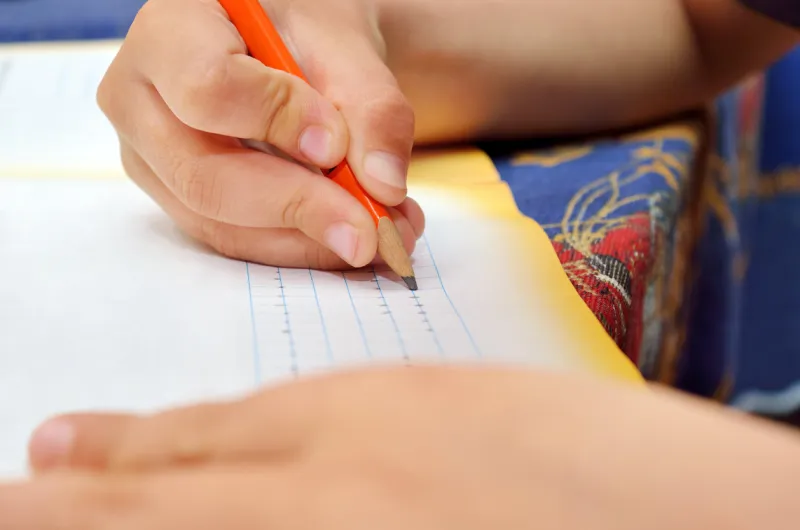 little boy diligently writes with a pencil in his notebook preschool education of children and pedagogy