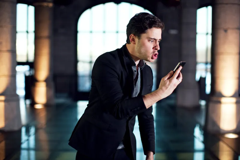 homme colérique face à son téléphone
