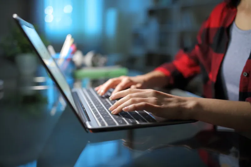 student hands typing on laptop in the night