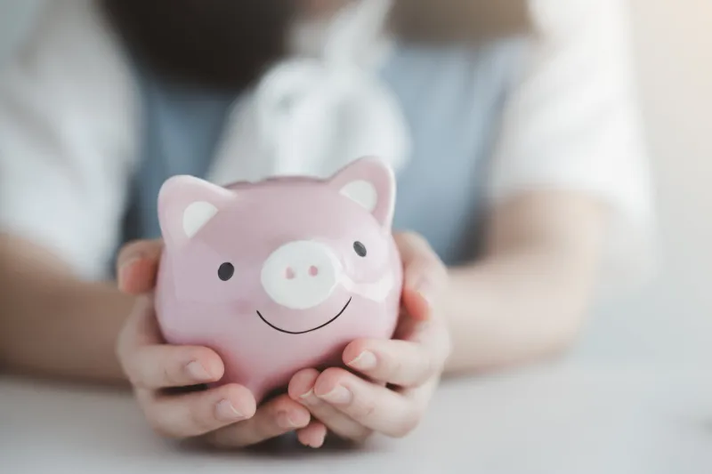 female hand holding pink piggy bank save money for future or retirement and financial investment