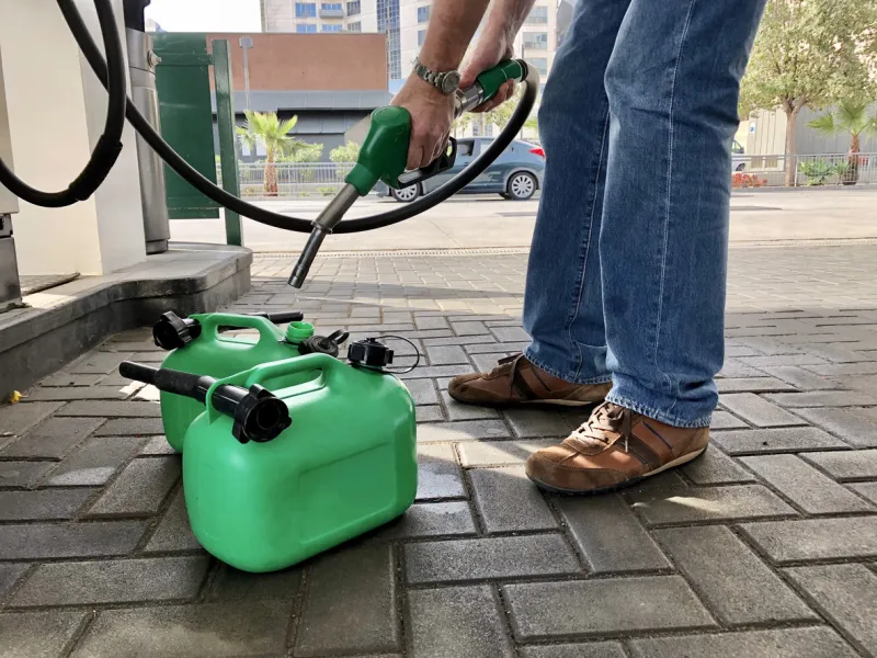 man filling plastic fuel cans at a petrol station