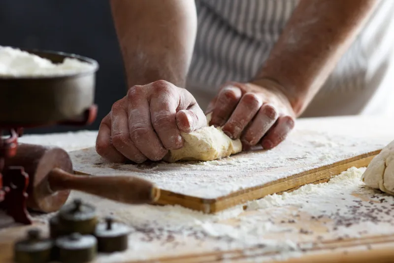 close up of male baker hands kneading the dough with flour powder