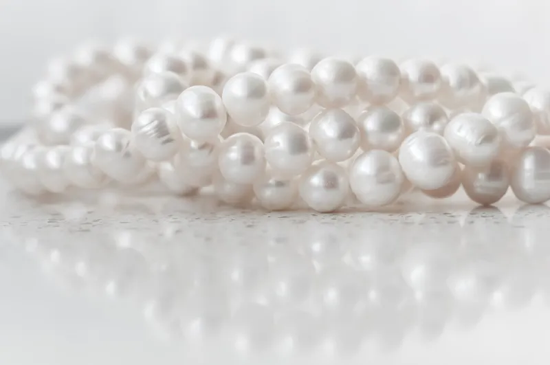 nature white string of pearls on marble background in soft focus, with highlights