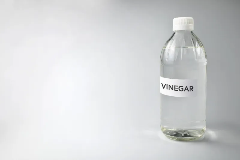 close-up of vinegar text on glass bottle against gray background