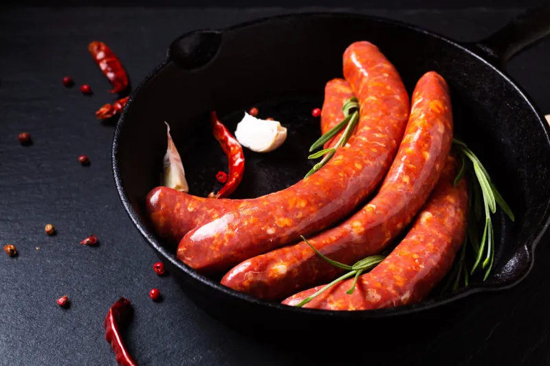 food concept merguez french spicy sausages in skillet iron pan with copy space