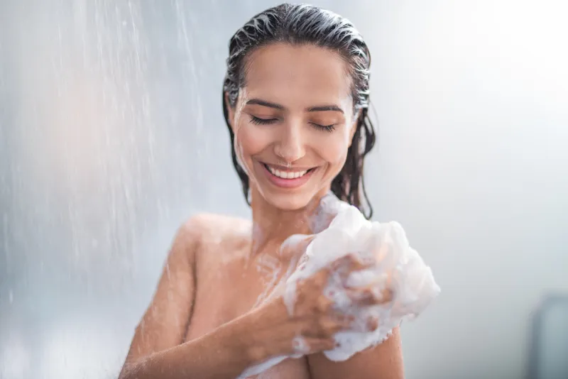 portrait of happy girl taking shower with gel she washing with puff