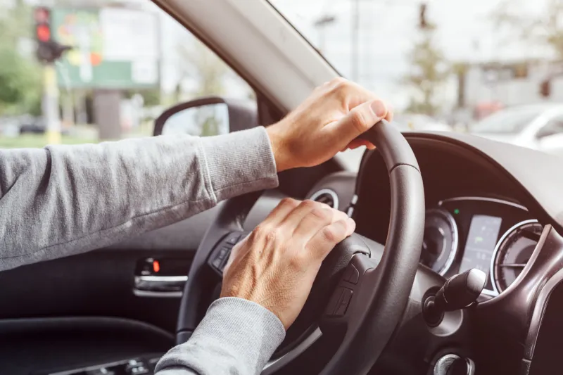 angry annoyed driver pushing car horn on steering wheel, close up of hand with selective focus