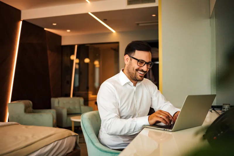 happy businessman using laptop in the hotel room, portrait