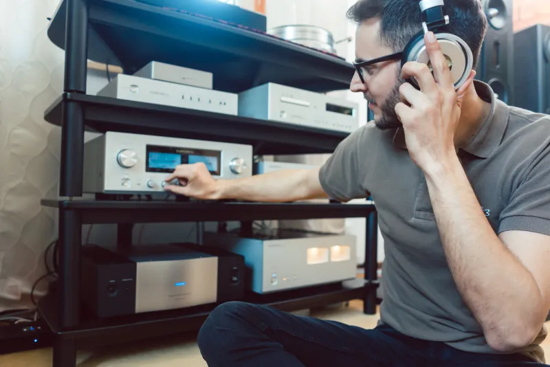 man turning up the volume on home hi-fi stereo for louder music