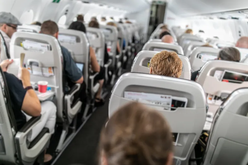 interior of commercial airplane with passengers in their seats during flight