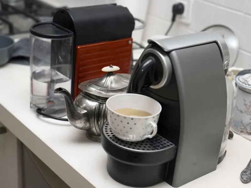 tea pot between two coffee makers on the kitchen table, indoor close-up