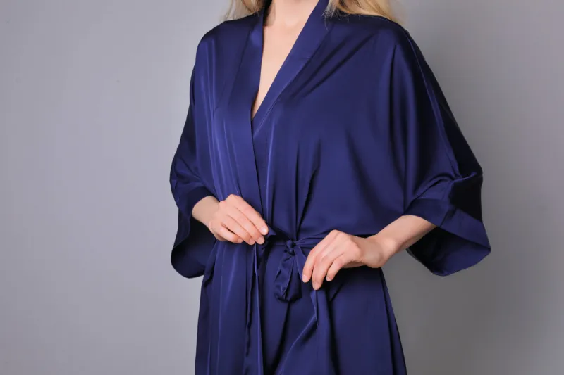 woman in beautiful dark blue silk robe on grey background, closeup