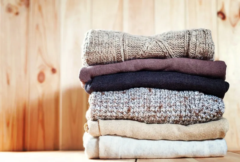 knit cozy sweater folded in a pile on wooden background warm the concept copyspace