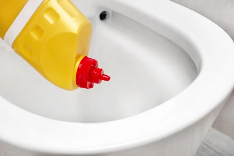 pouring cleaner for toilet to lavatory bowl close up
