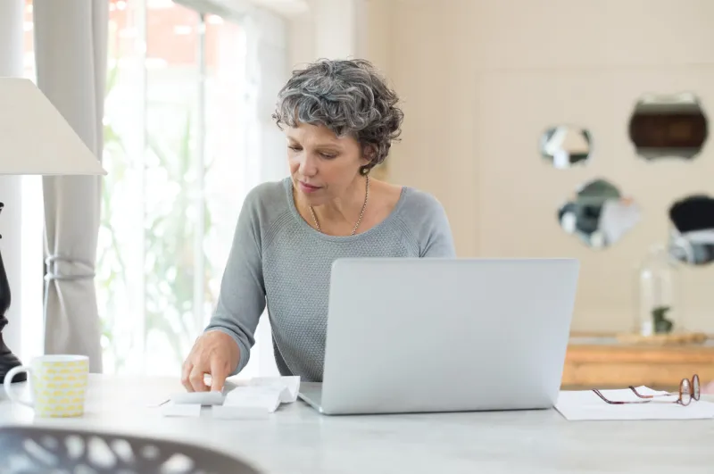 senior woman working on home finance mature woman checking bills at home older woman checking pension approval certificate with laptop at home