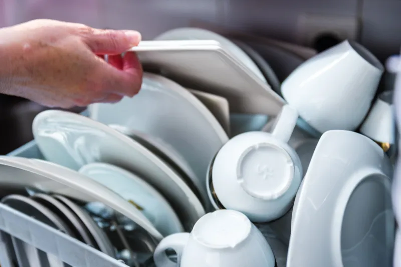 woman loading dishes and silverware into dishwasher in the kitchen