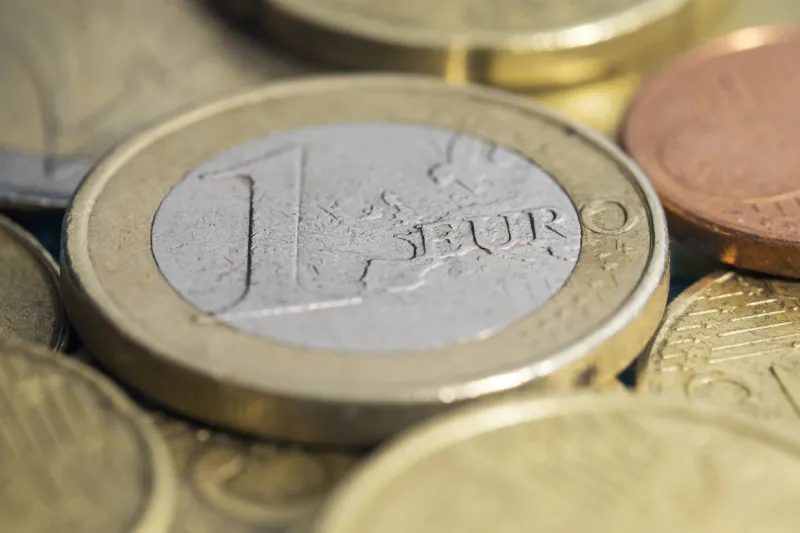 macro photography of a one euro coin with the focus on the euro letters and the background very out of focus euro coins stacked with selective focus on the 1 and the word euro european coins