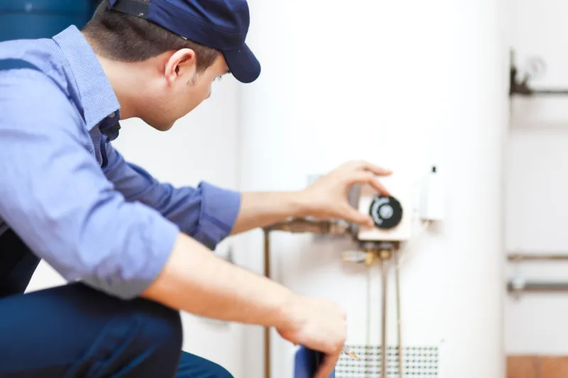 smiling technician repairing an hot-water heater