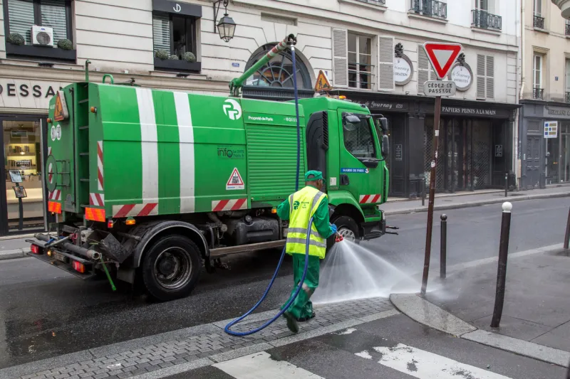 paris, france - july 24, 2017  a sweeper car and a worker cleaning the streets