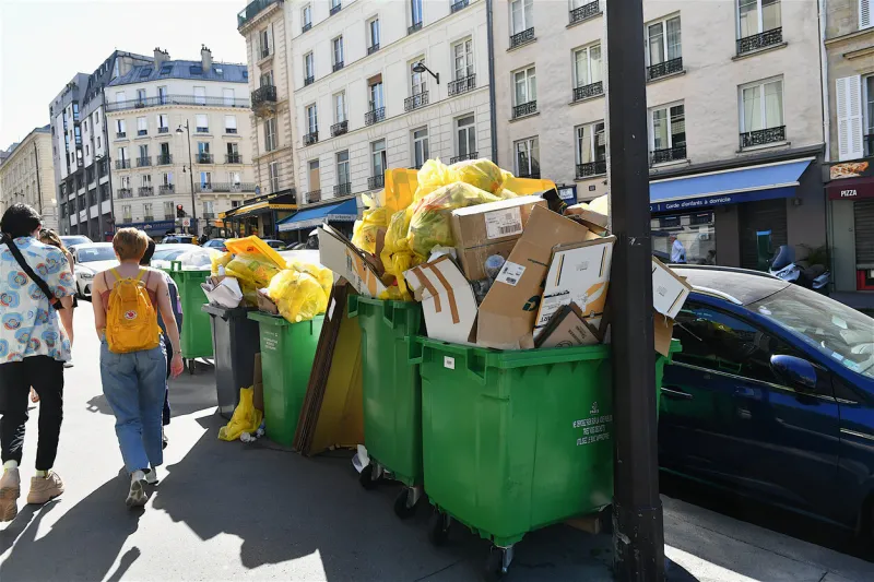 paris, france-06 16 2022 people passing next to overflowing garbages cans during a strike by parisian garbage collectors, france