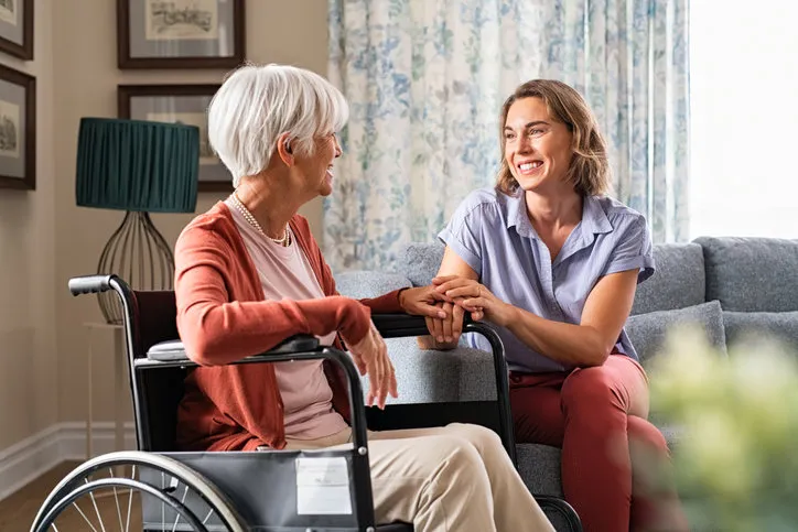 mature woman comforting senior mom sitting on wheelchair at nursing home cheerful woman talking to old disabled mother in wheelchair at elder care centre loving caregiver taking care of elderly woman at home