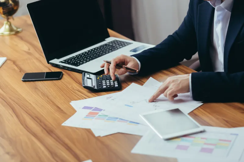 close-up photo, businessman accountant's hand counts on a calculator, man sitting at a table paperwork