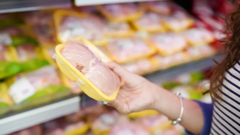 meat in food store woman choosing packed fresh chicken meat in supermarket