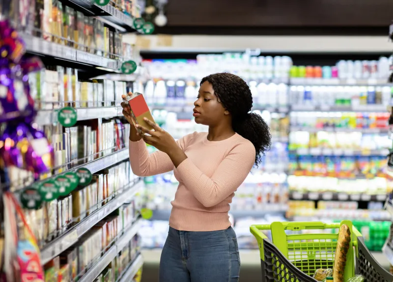 pretty african american woman choosing groceries at supermarket, shopping for food, buying products for her family female consumer purchasing goods at huge mall, walking among shelves