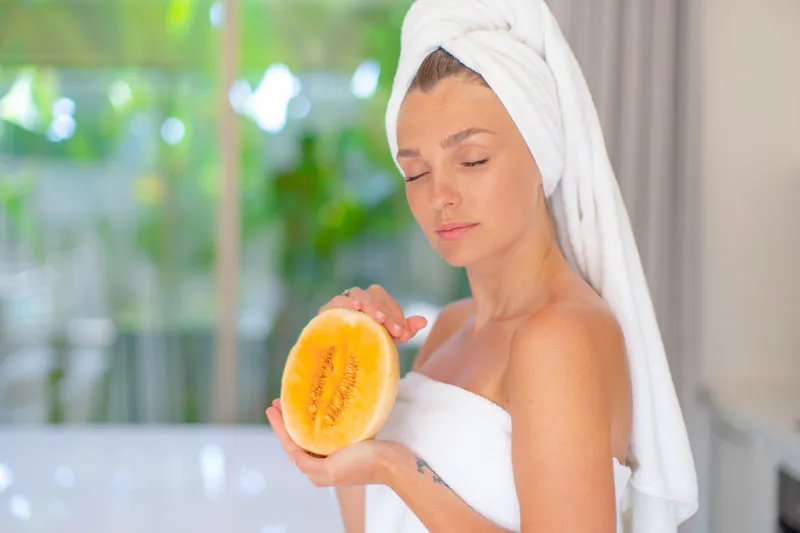 a beautiful young girl in her hands holds a fresh fruit, a melon
