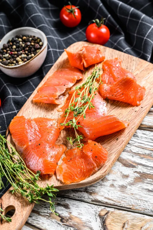 salted salmon slices with pepper and thyme organic fish white background top view