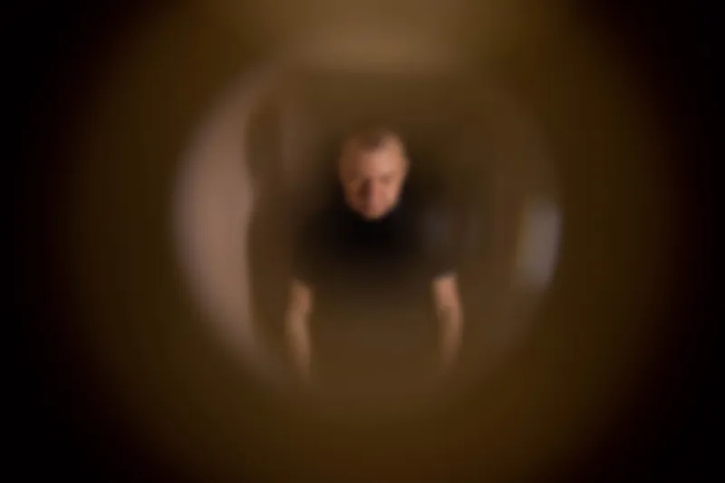 a male apartment burglar stands on the stairwell and peers through the peephole, close-up the concept of theft in apartments, blurry