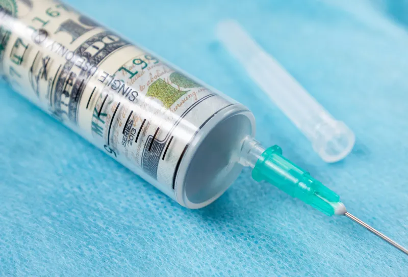 syringe and us dollars symbolic image of the high cost of treatment, medication, drugs and medical insurance