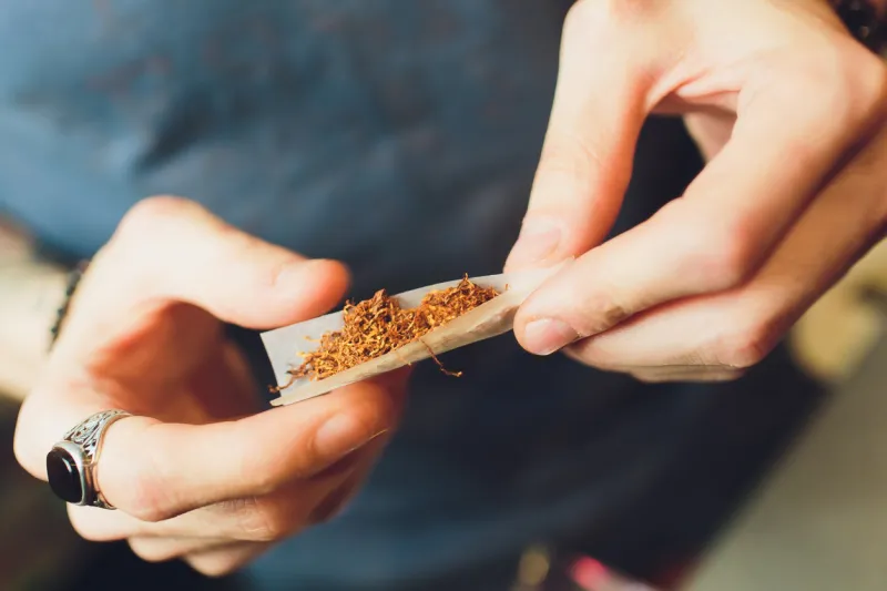 hands of a man rolling a cigarette the concept of marijuana, drugs, addiction