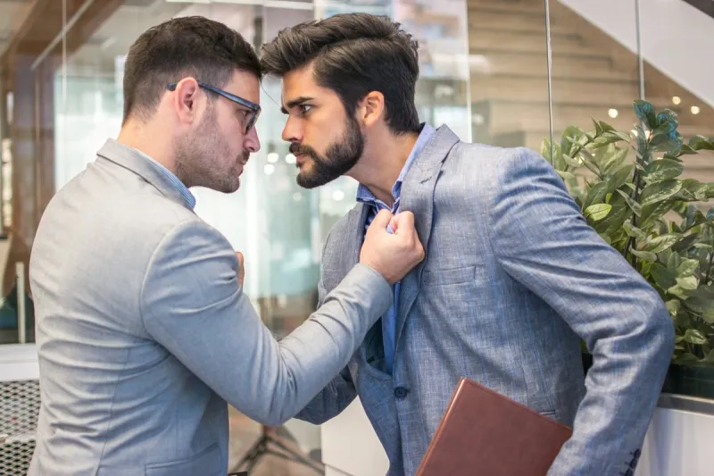 business conflict between two business men in formal-wear in office boss and employee with aggressive expression fight