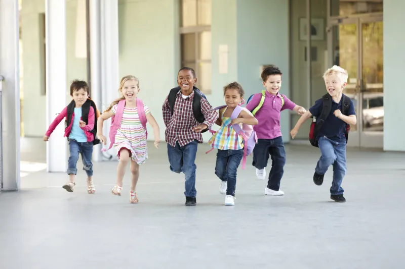 group of elementary age schoolchildren running outside