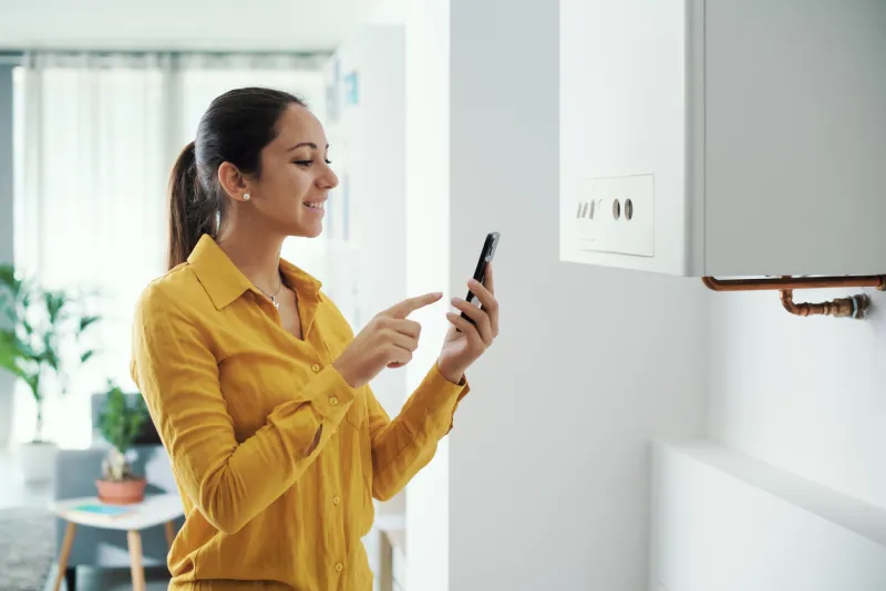 woman managing and programming her smart boiler using her smartphone, smart home concept