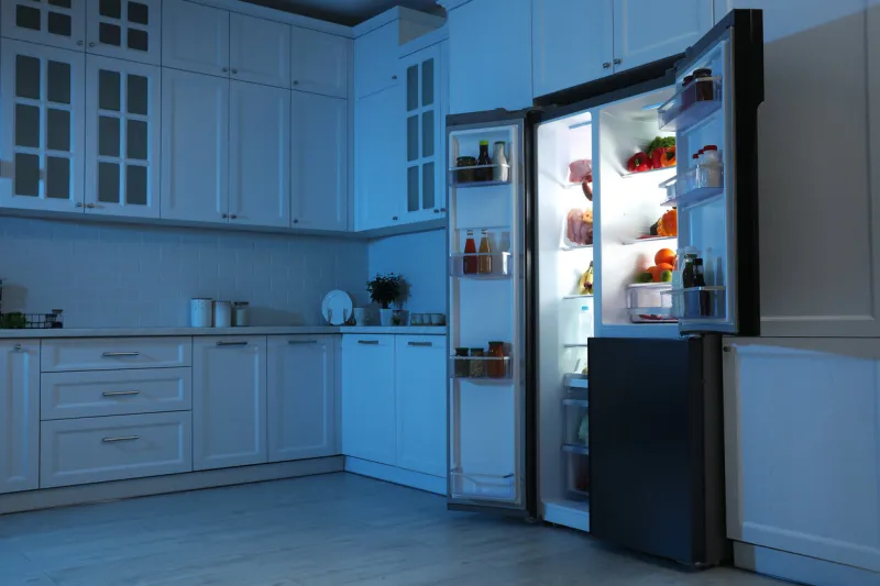 open refrigerator filled with food in kitchen at night