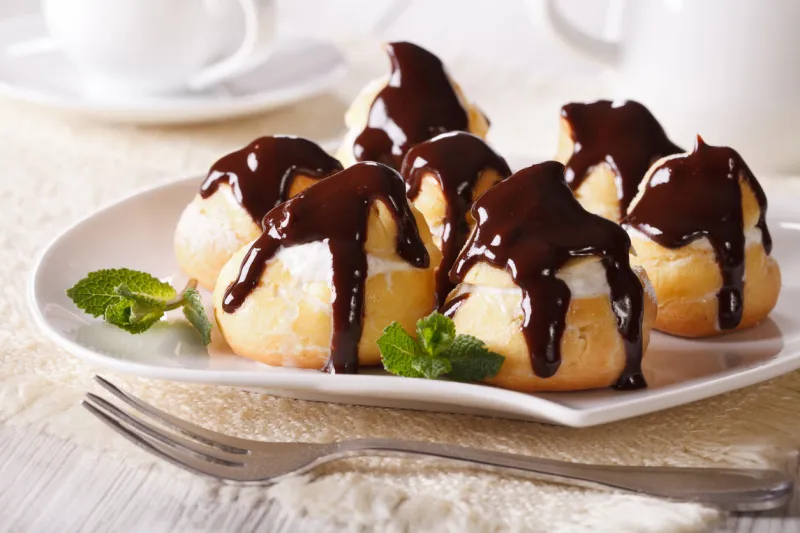 delicious eclairs with cream and chocolate frosting on a plate horizontal