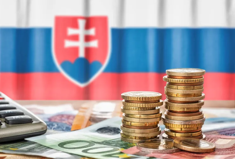 euro banknotes and coins in front of the national flag of slovakia