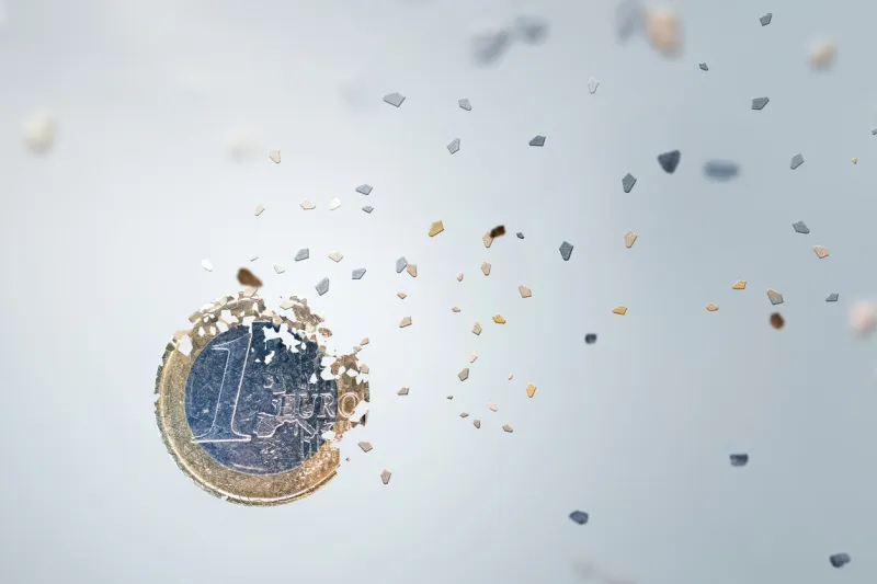 economic concept one euro coin breaking into small pieces isolated on neutral background