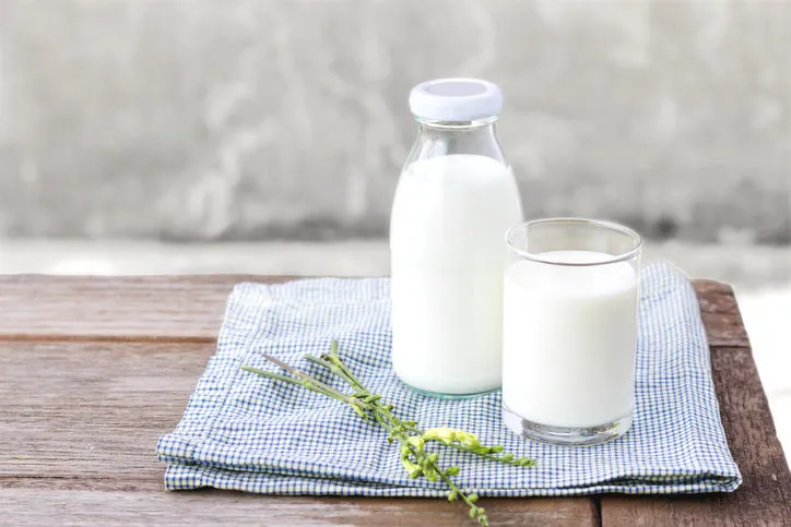 glass of milk and bottle of milk on the wood table with copy space for text