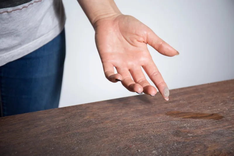 close-up of dust on woman finger taken from wooden table