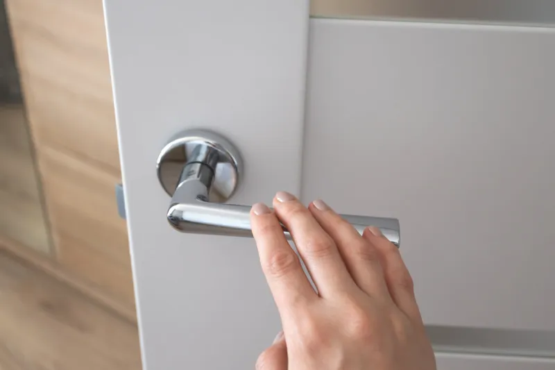 female hand on metal door handle modern interior detail