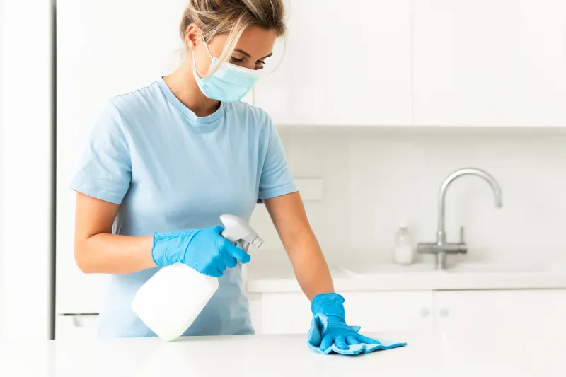 young woman worker wearing prevention mask and gloves during apartment cleaning
