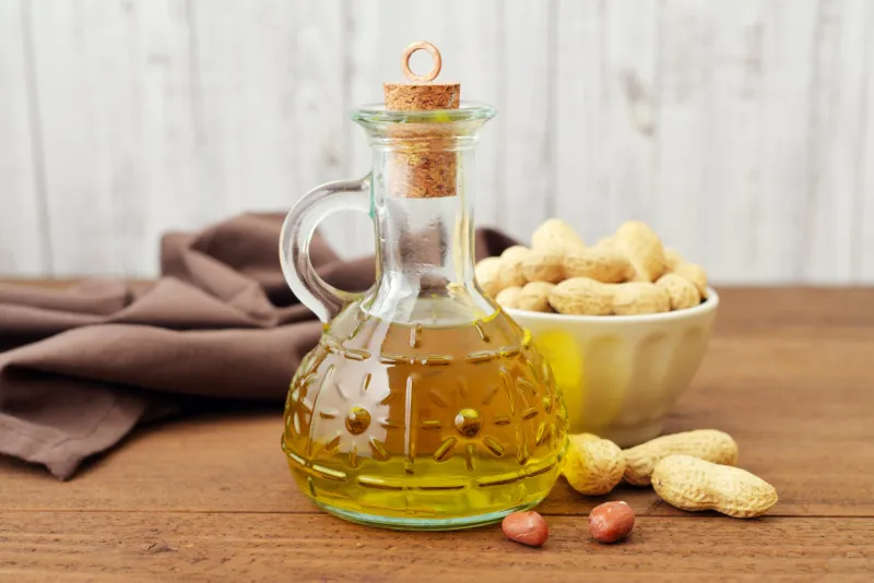 peanut oil with raw peanuts on wooden background